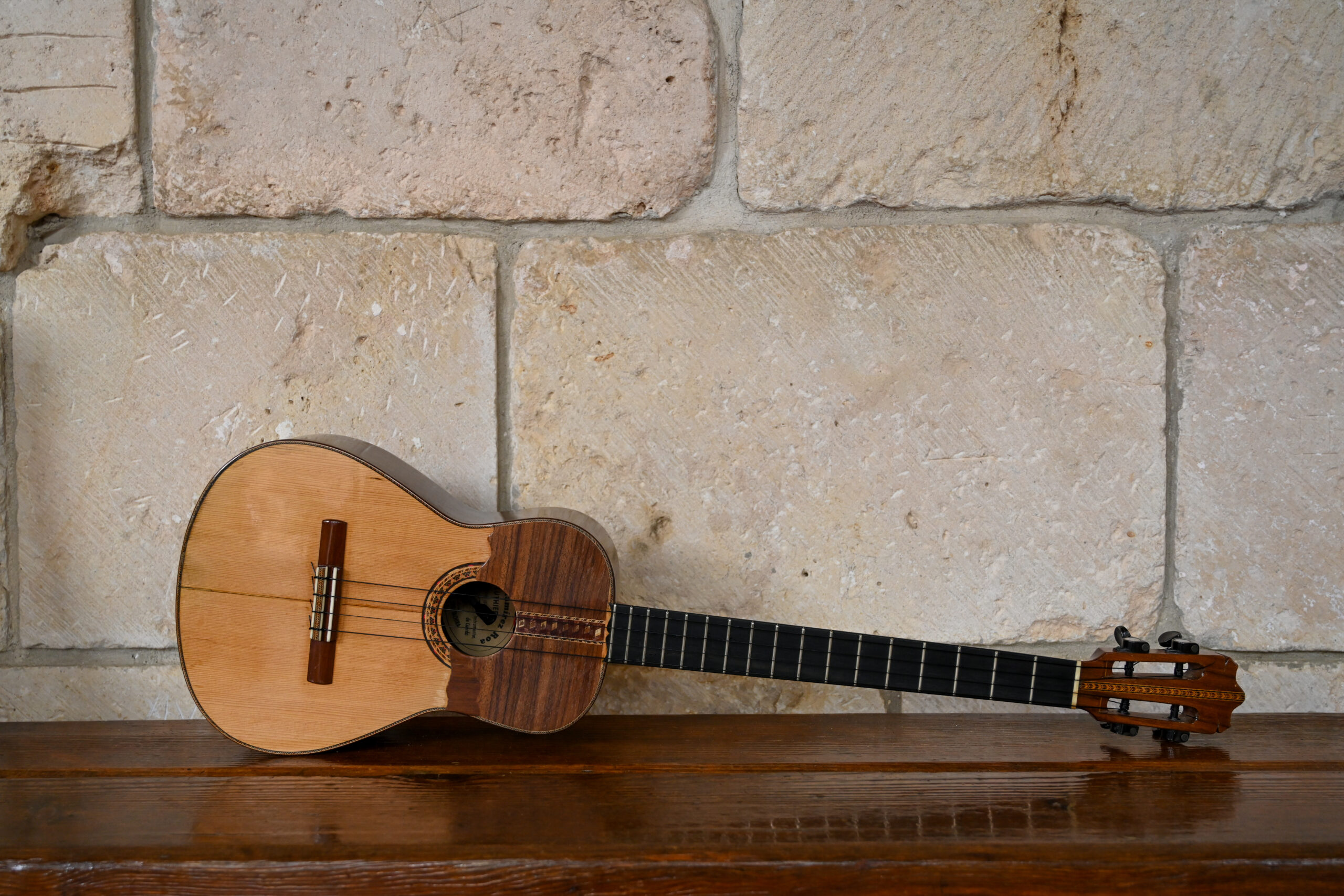 A cuatro guitar propped on its side on a bench
