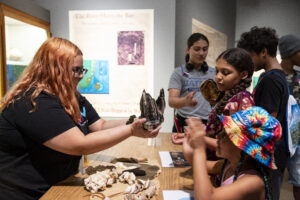 Museum staff with collection items presented to visitors.