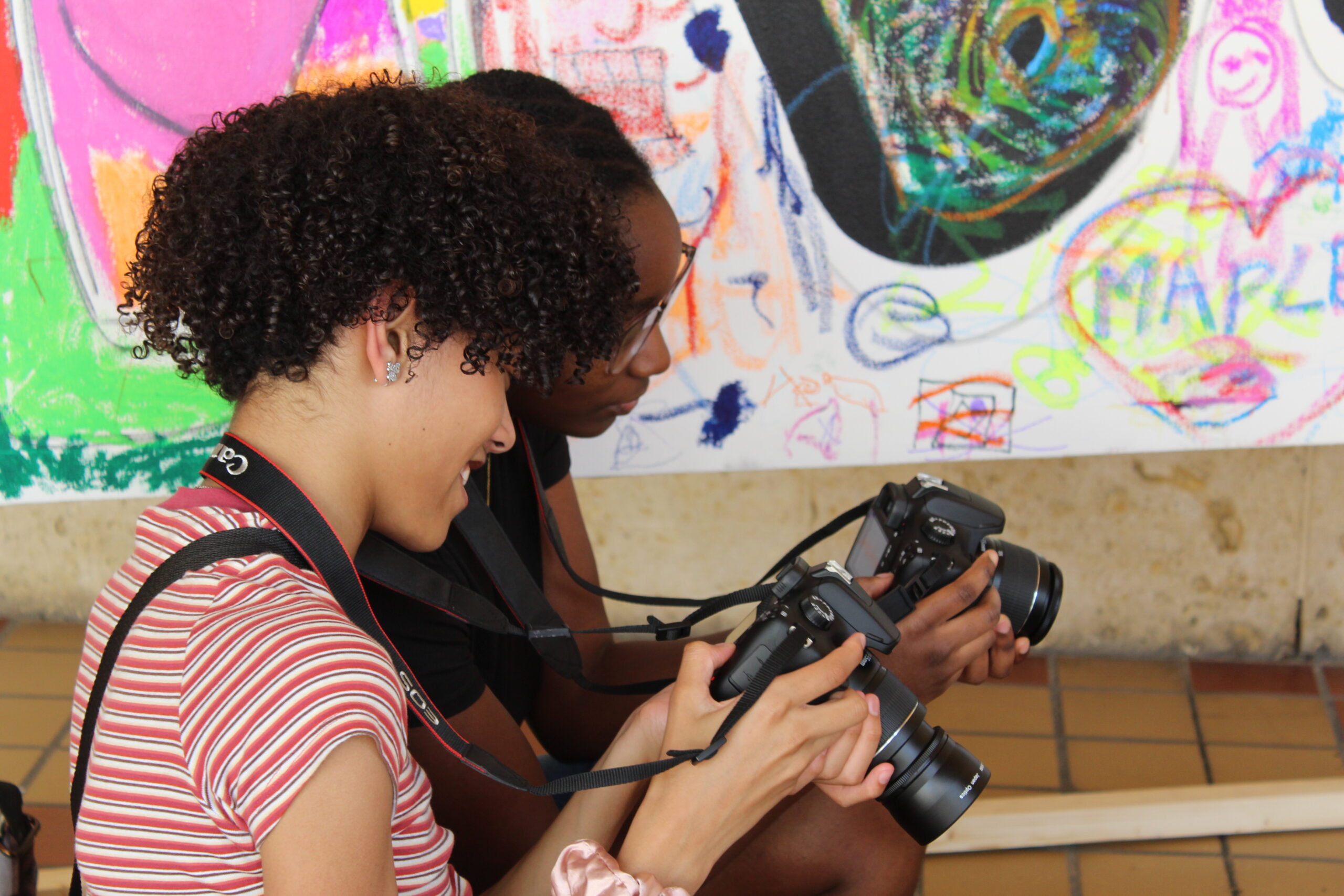 Two teens looking at pictures on their digital cameras.