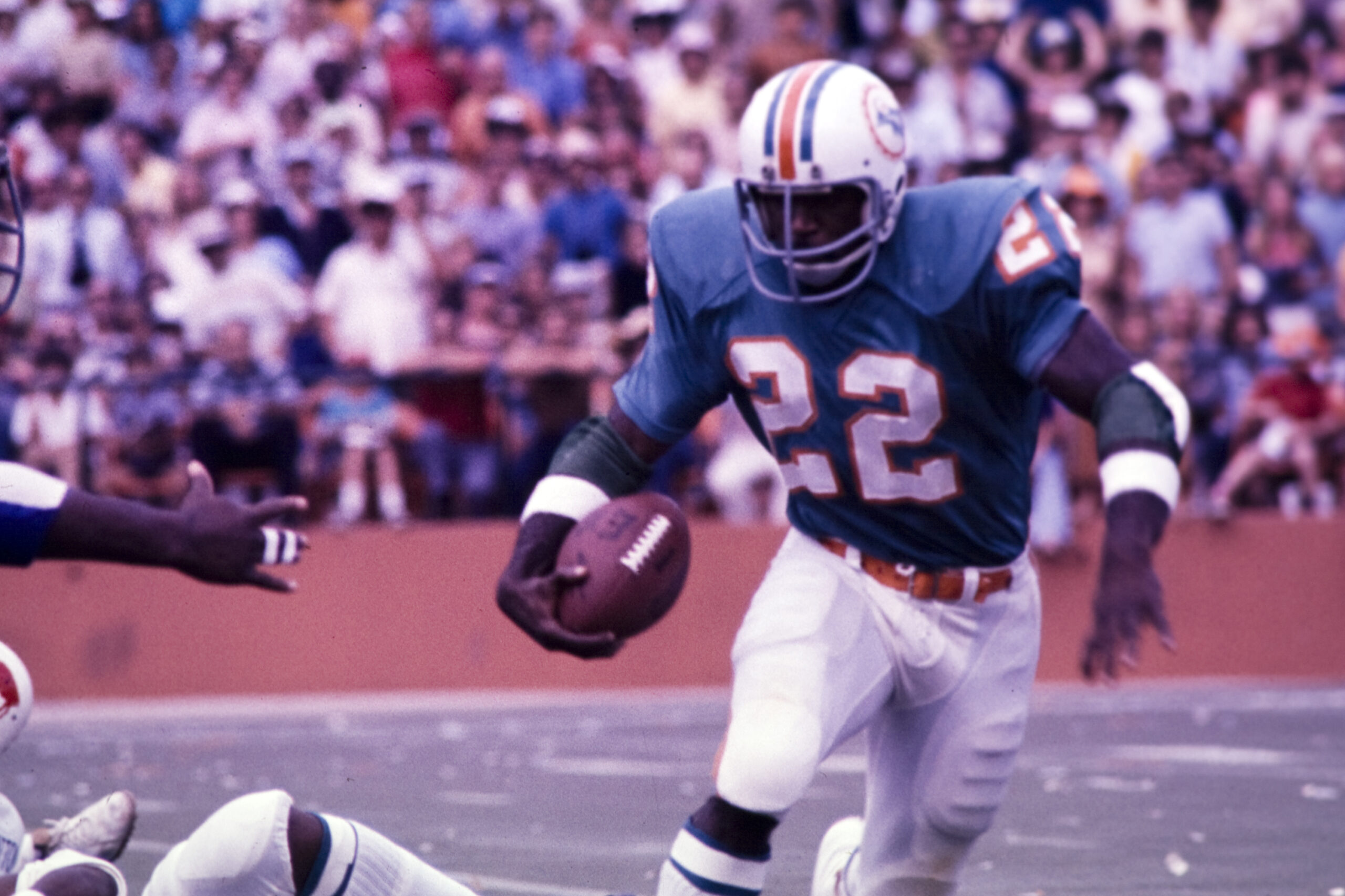 An action shot of a Miami Dolphins player, number 22, running with the ball.