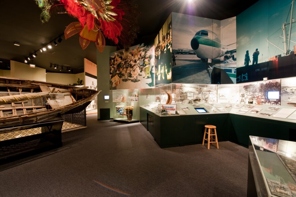 View of a museum exhibition with large scale photos and artifacts aligning the walls.