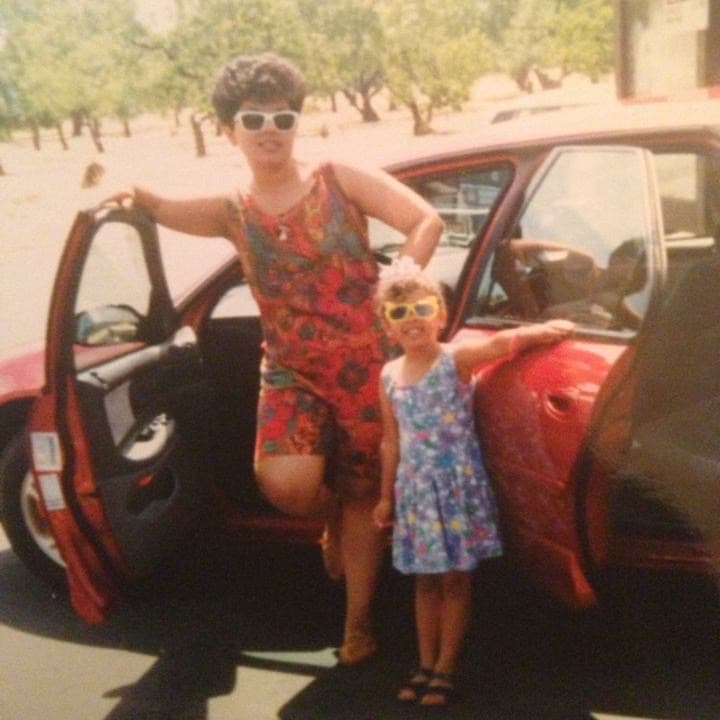 old image of an adult and child next to a car